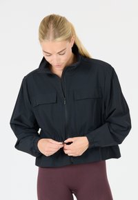 Black cropped jacket with a high collar, two front pockets, and elastic cuffs. The fabric appears lightweight and smooth, with a zip closure.