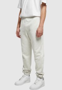 Ljusgrå mjukisbyxor i ett mjukt, fleecematerial med elastisk midja, tillsammans med vita sneakers.