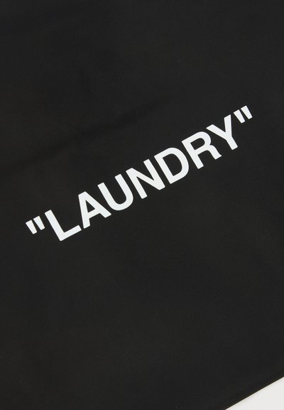 Μαύρο ύφασμα με λευκό κείμενο που γράφει «LAUNDRY» σε εισαγωγικά, τοποθετημένο διαγωνίως στην επιφάνεια.
