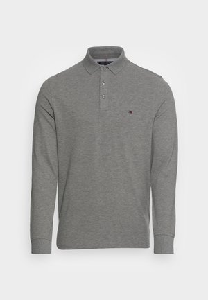 Polo à manches longues gris en coton doux. Il présente une patte à deux boutons et un petit logo brodé sur la poitrine gauche.