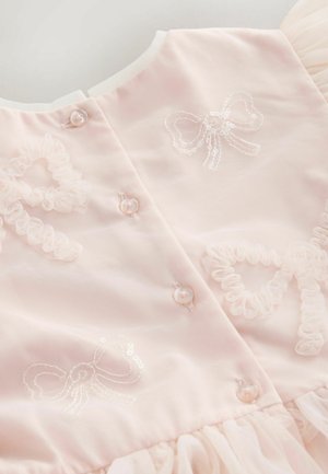 Gaiši rozā kleita no mīksta auduma, ar izšūtiem lokiem, volāniem un pērļu pogām muguras daļā.