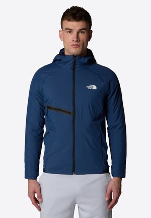 Giacca leggera blu con zip frontale, tasche laterali e cappuccio. Presenta accenti neri e un logo nella zona del petto.