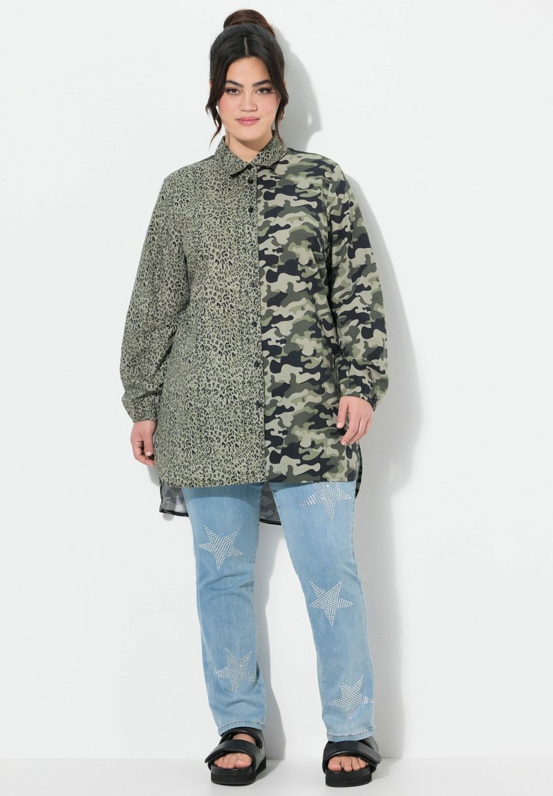 Camouflage- und Leopardenmuster-Hemd mit langen Ärmeln, kombiniert mit hellblauen Jeans, die mit Strassstern-Akzenten versehen sind, und schwarzen Sandalen.