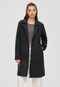 Grau melierter Wollmischmantel mit Reverskragen, zwei Knöpfen und seitlichen Taschen. Getragen über einem gestreiften Cropped-Top mit langen Ärmeln.