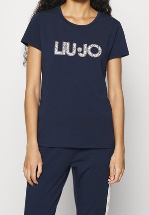 Donna con maglietta blu navy a maniche corte con logo "LIU·JO" in lettere bianche decorate e pantaloni blu navy coordinati con strisce laterali.