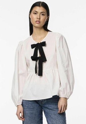 Blouse blanche avec des manches bouffantes, un col rond et un détail en nœud noir au centre. Tissu lisse avec un design en peplum.
