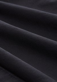 Czarna, teksturowana tkanina z subtelnym, prążkowanym wzorem, charakteryzująca się gładkimi, miękkimi fałdami i jednolitą, głęboką barwą. Idealna do różnych zastosowań.