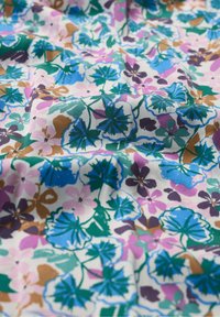 Tissu fleuri avec un fond blanc présentant des fleurs multicolores dans des nuances de bleu, violet, rose et vert, avec des motifs de feuilles détaillés.