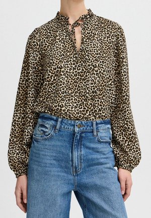 Blouse à imprimé léopard avec un col volanté, un décolleté en trou de serrure et des manches longues, associée à un jean en denim bleu taille haute.