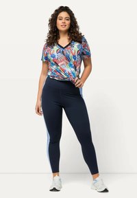 Flerfärgad kortärmad v-ringad tröja med blommönster, som matchas med marinblå tights med ljusblå sidostripes.