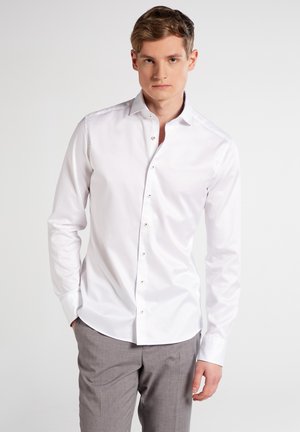 Weißes Button-Up-Hemd mit langen Ärmeln, taillierte Passform, aus weichem Baumwollstoff und klassischem Kragen. Die Knöpfe sind hellbraun und bieten einen subtilen Kontrast.