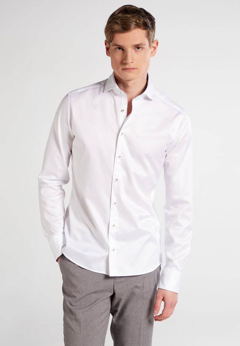 Weißes Button-Up-Hemd mit langen Ärmeln, taillierte Passform, aus weichem Baumwollstoff und klassischem Kragen. Die Knöpfe sind hellbraun und bieten einen subtilen Kontrast.
