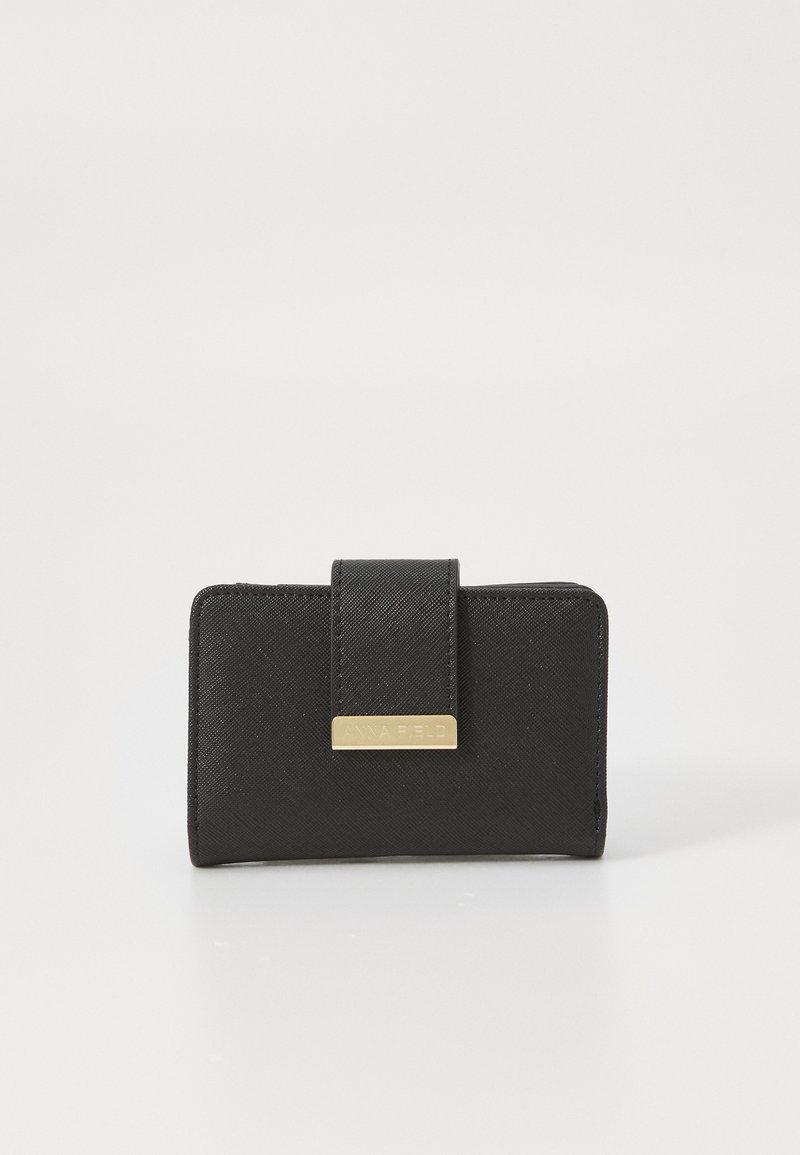 Portefeuille noir en matériau texturé, orné d'une quincaillerie dorée avec le nom de la marque. Forme rectangulaire compacte avec un fermoir.