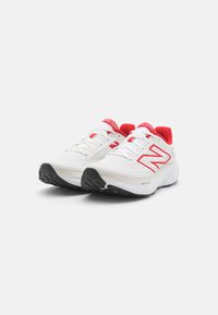 Ténis atléticos brancos com detalhes em vermelho, parte superior em malha, colarinho acolchoado, fecho com cordões e sola em borracha preta. Apresenta o logo "N" na lateral.