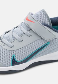 Gray athletic shoe with mesh upper, blue interior, turquoise and navy accents, and a hook-and-loop strap over laces.