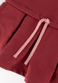 Burgunderfarbiges Kleidungsstück mit einem gefältelten Design, das an der Taille mit einem rosa Kordelzug gebunden ist. Weicher Stoff mit sauberem Nähdetail.