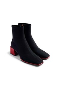 Stivaletti neri alla caviglia con texture rigata, punta quadrata e tacco a blocco rosso. Presentano una zip laterale per un facile indossamento.