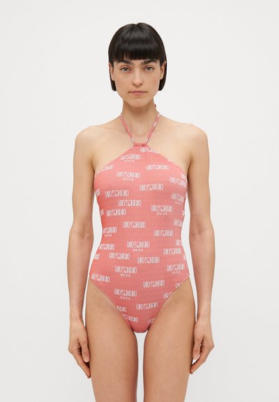 Rózsaszín, nyakba akasztós egyrészes fürdőruha, melyen a "Moschino" logó ismétlődik. Simább textúra és testhez simuló forma. Egyszerű dizájn minimális fém részekkel.