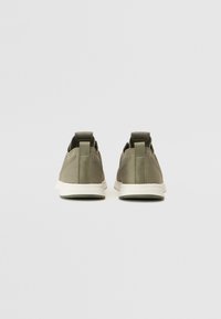 Szare siateczkowe sneakersy o strukturalnym wykończeniu, białych podeszwach i dwóch tylnych uchwytach ułatwiających zakładanie. Minimalistyczny design z prostymi akcentami.