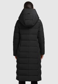 Fekete puffermellény, hosszú kialakítással, nagy kapucnival és steppelt textúrával. Simább anyag, látható varrással és letisztult kinézettel.
