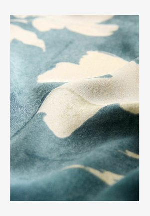 Tissu à motif avec une texture douce, présentant un fond bleu avec des formes florales beiges, créant une apparence fluide et organique.