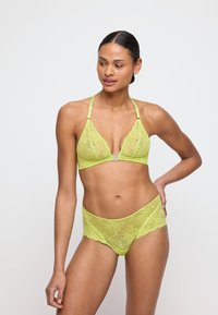 Soutien-gorge en dentelle vert lime et ensemble de culotte assorti, mettant en avant de délicats motifs floraux, des bretelles ajustables et un bord lisse à volants.