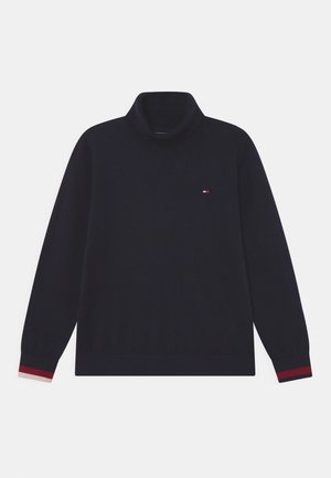 Marineblå sweater med høj polokrave, lange ærmer og ribstrikkede manchetter. Har et lille broderet logo på brystet og kontrasterende stribede detaljer på ærmerne.