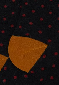 Calzini neri con pois rossi, dotati di una punta e un tallone rinforzati arancioni. Texture morbida, design aderente e polsino elastico.