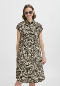 Abito camicia con stampa leopardata, maniche corte, chiusura con bottoni sul davanti, vestibilità rilassata, nei toni del beige e del nero, con una texture di tessuto liscia.