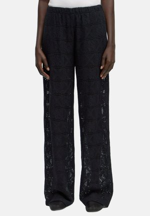 Schwarze gehäkelte weit geschnittene Hosen mit einem komplexen geometrischen Muster, ausgestattet mit einem elastischen Bund und einem leichten Material.