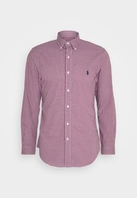 Červená a bílá kostkovaná košile s dlouhým rukávem, límečkem na knoflíky, předními knoflíky a malým vyšívaným logem na kapse na prsou. Rovnoměrná textura.