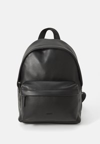 Zaino in pelle nera con tasca frontale con zip, manico superiore e logo "HUGO" sul taschino frontale, su sfondo bianco.