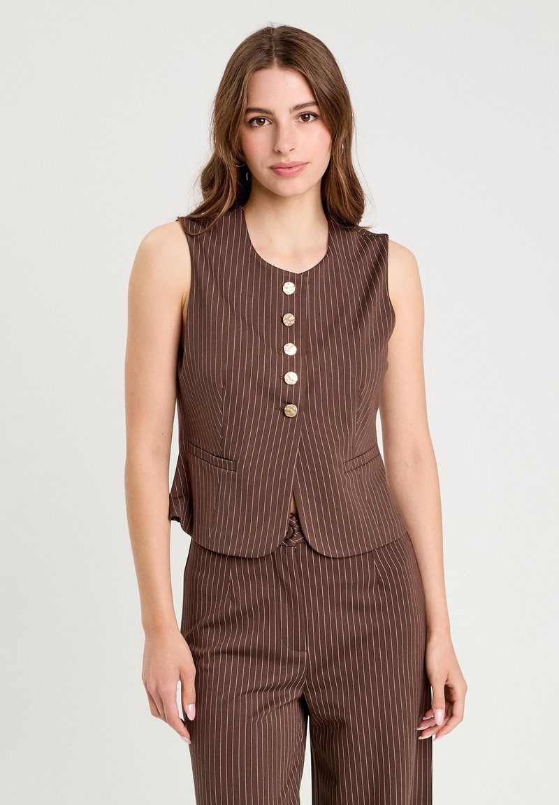 Gilet senza maniche marrone a righe sottili con scollo rotondo, cinque bottoni frontali e due tasche laterali. Tessuto liscio con vestibilità sagomata.