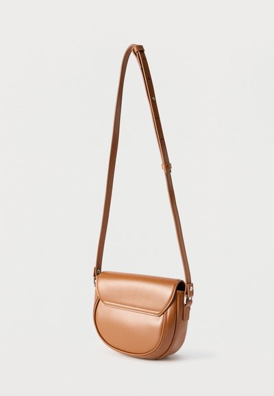 Καφέ δερμάτινη τσάντα χιαστί με ρυθμιζόμενο λουρί και στρογγυλεμένο κάτω μέρος, εμφανίζεται σε απλό λευκό φόντο.