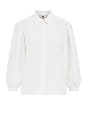 Camicia bianca con colletto, maniche a palloncino e tessuto testurizzato. Presenta una pattina frontale con bottoni.