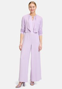 Lavendel Jumpsuit mit tailliertem Oberteil und weitem Bein, ergänzt durch eine kurze Lavendel-Cardigan. Sanfter, leichter Stoff.