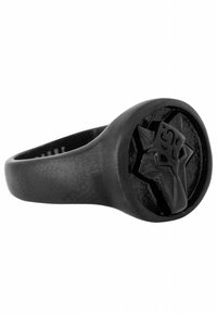 Anillo de metal negro con una cara redonda y texturada que presenta un diseño elevado de una estrella y la cabeza de un león. Banda lisa y pulida con acabado mate.