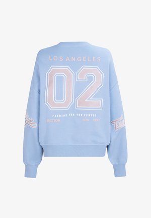 Sweat-shirt bleu clair avec un col rond, des épaules tombantes, et de grandes lettres blanches et roses au dos, comprenant "LOS ANGELES" et "02."