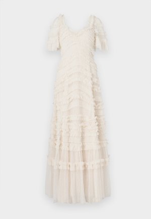 Λευκό, μακρύ φόρεμα με βολάν και κοντά φουσκωτά μανίκια, με υφή υφάσματος και στρώσεις διάφανου, πουα υλικού στο κάτω μέρος.