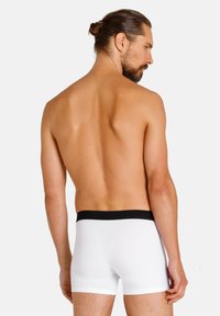 Weiße Boxershorts mit einem schwarzen Bund, die eine glatte Baumwollstruktur aufweisen. Das Modell ist von hinten zu sehen, was ein einfaches Design offenbart.