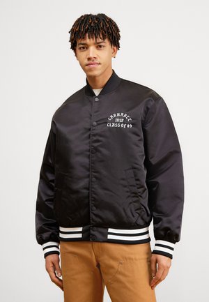 Black satin bomber jacket with white lettering “CARHARTT CLASS OF 89” on chest. Features striped ribbed cuffs and waistband, side pockets.