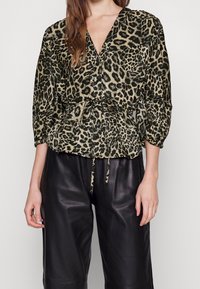 Blouse à imprimé léopard en tissu doux, avec un col en V, une taille froncée et des manches trois-quarts, associée à un pantalon en similicuir noir.