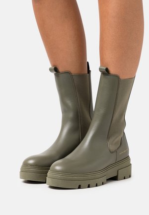 Vihreät nahkaiset nilkkurit, joissa joustavat sivupaneelit, teksturoitu pinta ja paksut kumipohjat, joissa on syvät urat pitoon.