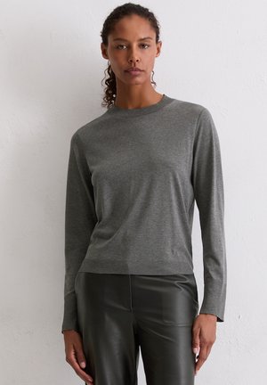Grijs langemouwen shirt van zachte stof, met een ronde hals en een ontspannen pasvorm. Gecombineerd met strakke zwarte leren broek.