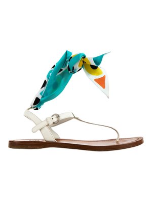 Flat sandal with white leather straps, brown sole, and a colorful turquoise, yellow, black, and orange patterned fabric tied around the ankle.