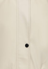 Ελαφρύ κρεμ χρώματος συνθετικό δερμάτινο μπουφάν με γυαλιστερό φινίρισμα, που διαθέτει κλείσιμο με μαύρα κουμπιά και ραφές κατά μήκος της μπροστινής ραφής.