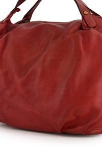 Red leather handbag with a soft, textured surface. Features rounded shape and dual handles; zipper closure at the top.