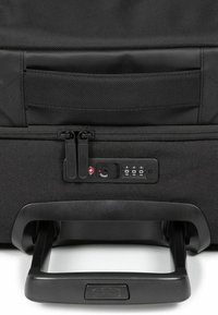 Black wheeled suitcase featuring a durable fabric exterior, dual zippers, combination lock, and an extendable handle.