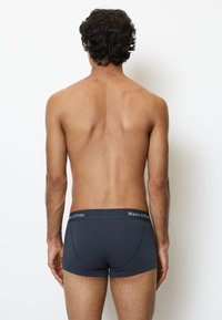 Boxer in grigio scuro con una texture liscia e una vestibilità aderente, caratterizzati da un cinturino nero a contrasto con il logo "Marc O'Polo" stampato.