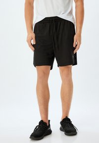 Sorte atletiske shorts med elastisk talje og snor, har sidelommer og et reflekslogo accent på benet.